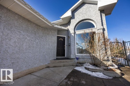 The property features stucco exterior, an arched window, and a dark paneled entry door - 3772 30 Street, Edmonton, AB - Outdoor