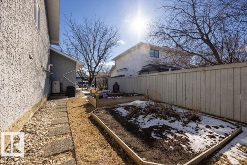 The property features a concrete stepping stone pathway alongside the building leading to a backyard area with a wooden fence and raised garden beds - 3772 30 Street, Edmonton, AB - Outdoor