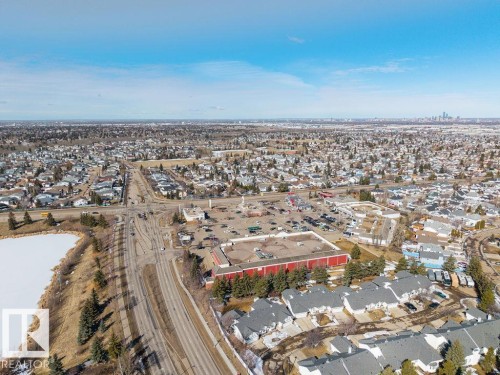 Aerial view showcasing the surrounding neighborhood with residential properties, a commercial area, and a distant city skyline - 3772 30 Street, Edmonton, AB - Outdoor With View
