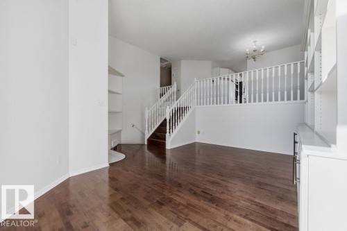 Living area featuring hardwood flooring, white walls, and a staircase with white railings - 3772 30 Street, Edmonton, AB - Indoor