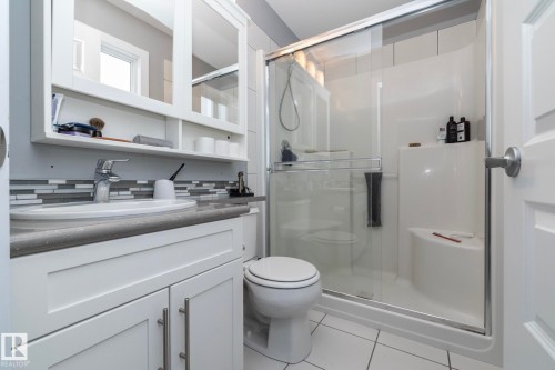 The bathroom features a white vanity with cabinet storage and a mirror, a tiled shower with a clear glass enclosure, and a toilet - 7359 179 Avenue, Edmonton, AB - Indoor Photo Showing Bathroom