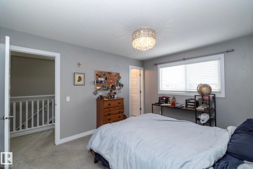 This room features a window with blinds, carpeted flooring, and a decorative ceiling light fixture - 7359 179 Avenue, Edmonton, AB - Indoor Photo Showing Bedroom