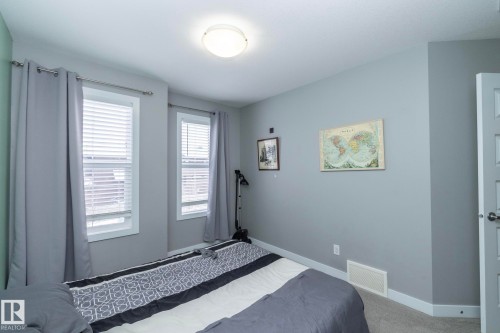 This room features light grey walls, two windows with blinds, and light carpet flooring - 7359 179 Avenue, Edmonton, AB - Indoor Photo Showing Bedroom