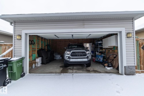 The property includes a detached garage with light-colored siding, a wide overhead door, and exterior lighting fixtures - 7359 179 Avenue, Edmonton, AB - Outdoor With Exterior