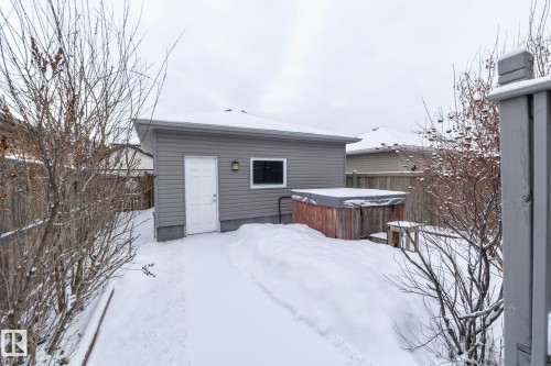 The property features a detached garage with gray siding and a white access door, alongside a hot tub with a wooden exterior and a protective cover - 7359 179 Avenue, Edmonton, AB - Outdoor With Exterior