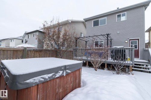 The property features a wooden deck with a black metal pergola, an outdoor light fixture, and a brown back door with a window - 7359 179 Avenue, Edmonton, AB - Outdoor With Deck Patio Veranda With Exterior