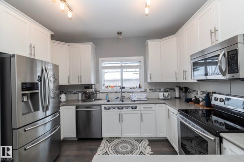 The kitchen features white cabinetry, stainless steel appliances, and a window above the sink - 7359 179 Avenue, Edmonton, AB - Indoor Photo Showing Kitchen With Stainless Steel Kitchen