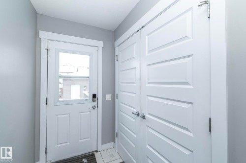 Entryway featuring a white door with a window pane, a digital lock, and an adjacent set of white paneled doors - 7359 179 Avenue, Edmonton, AB - Indoor Photo Showing Other Room