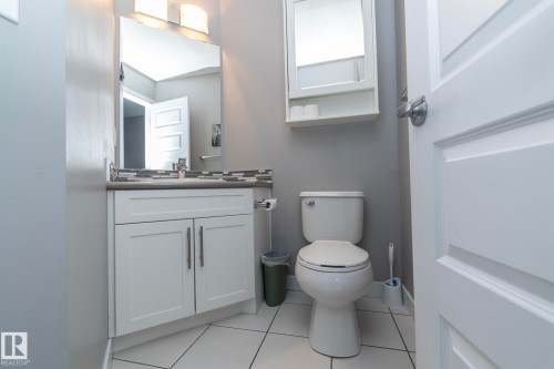 Bathroom featuring a vanity with white cabinetry, a rectangular mirror, and a white toilet - 7359 179 Avenue, Edmonton, AB - Indoor Photo Showing Bathroom
