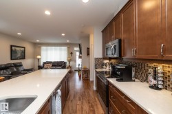 This kitchen features extensive cabinetry, stainless steel appliances, and a tiled backsplash, with a large island and ample counter space - 