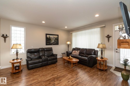 Spacious living area featuring durable wood-look flooring, recessed lighting, and a large window with vertical blinds - 307 Ravine Close, Devon, AB - Indoor Photo Showing Living Room