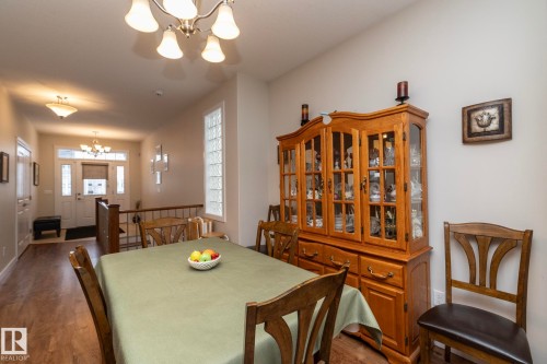 Dining area featuring a chandelier, hardwood flooring, and a glass block window - 307 Ravine Close, Devon, AB - Indoor Photo Showing Dining Room