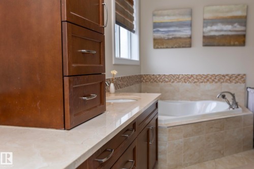 Bathroom featuring a built-in bathtub, a vanity with a light-colored countertop, and a window with blinds - 307 Ravine Close, Devon, AB - Indoor Photo Showing Bathroom