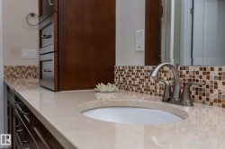 Bathroom vanity featuring a light-colored countertop, a built-in sink, and a brushed nickel faucet - 