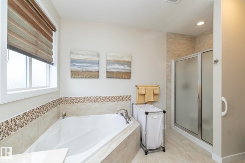 Bathroom featuring a corner bathtub, a glass-enclosed shower, and tiled walls - 307 Ravine Close, Devon, AB - Indoor Photo Showing Bathroom