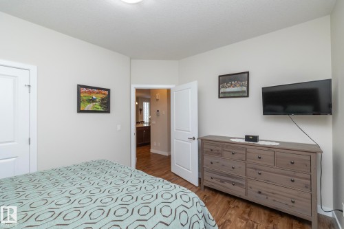 Well-appointed bedroom featuring light-colored walls, wood-style flooring, and a doorway leading to an additional space - 307 Ravine Close, Devon, AB - Indoor Photo Showing Bedroom