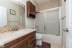 This bathroom features a vanity with a light-colored countertop and a mosaic tile backsplash - 