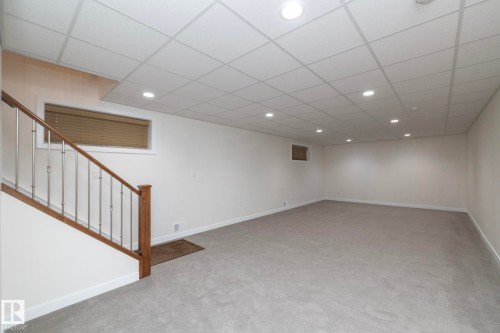Spacious room featuring light gray carpeting, recessed ceiling lighting, and a window with blinds - 307 Ravine Close, Devon, AB - Indoor Photo Showing Other Room