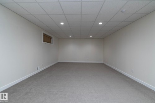 This spacious room features neutral-toned carpet flooring, white walls, and a dropped ceiling with recessed lighting - 307 Ravine Close, Devon, AB - Indoor Photo Showing Other Room