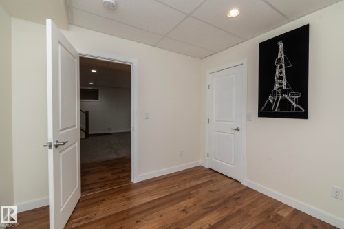 This room features rich hardwood flooring, light-colored walls, and a dropped ceiling with recessed lighting - 307 Ravine Close, Devon, AB - Indoor Photo Showing Other Room