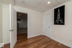 This room features rich hardwood flooring, light-colored walls, and a dropped ceiling with recessed lighting - 