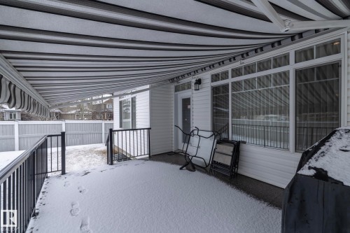 This property features a covered patio with a striped awning, white siding, and a large window - 307 Ravine Close, Devon, AB - Outdoor With Exterior
