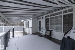 This property features a covered patio with a striped awning, white siding, and a large window - 
