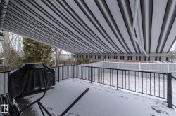 Outdoor deck space with a striped retractable awning, black metal railing, and privacy fencing - 