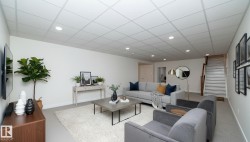 Spacious living area featuring a drop ceiling with recessed lighting, light-colored walls, and stairs with a wooden railing - 