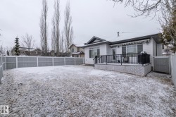 The property features a spacious yard with a deck, complete with a dark metal railing and white lattice skirting - 