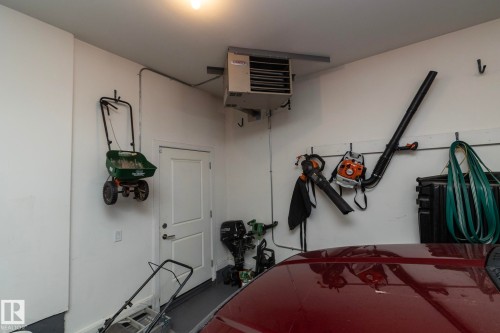 The garage features white walls, a white door, and a mounted heating unit - 307 Ravine Close, Devon, AB - Indoor