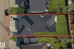 The property features a dark shingled roof, a paved driveway, and a well-maintained lawn - 