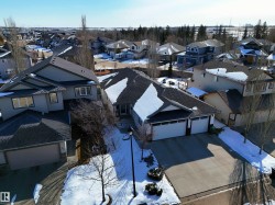 The property features a dark-colored roof, a concrete driveway, and an attached garage with two garage doors - 