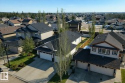 Aerial view of a residential neighborhood featuring properties with dark-shingled roofs, attached garages, and paved driveways - 