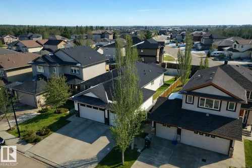 Aerial view of a residential neighborhood with several properties featuring paved driveways, green lawns, and mature trees - 307 Ravine Close, Devon, AB - Outdoor