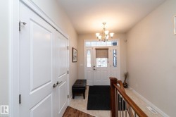 Entryway featuring a white door with glass panels, a classic chandelier, and a wood railing - 