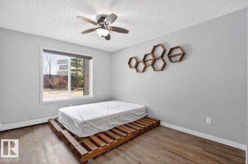 This room features a window providing natural light, a ceiling fan, and wood-look flooring - 109 340 Windermere Road, Edmonton, AB 