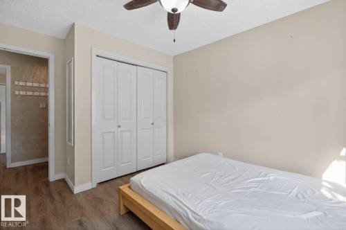 This bedroom offers light-colored walls, a ceiling fan, and bi-fold closet doors - 109 340 Windermere Road, Edmonton, AB 