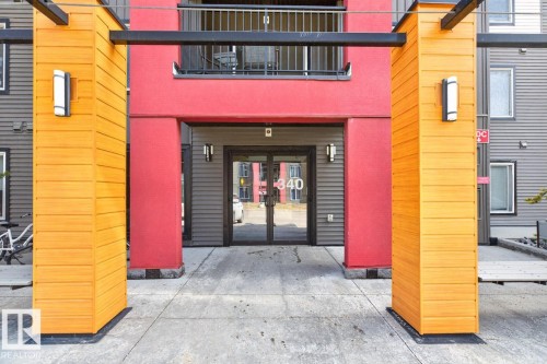 The property features a distinct exterior with vibrant red and natural wood-toned panels, complemented by dark grey siding - 109 340 Windermere Road, Edmonton, AB 