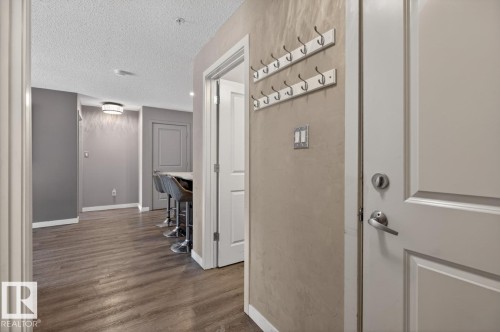 This property features durable wood-look flooring throughout, a modern light fixture, and neutral gray walls - 109 340 Windermere Road, Edmonton, AB 