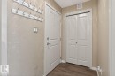 The property's entryway features a white door, light-colored walls, and two wall-mounted coat racks - 109 340 Windermere Road, Edmonton, AB 