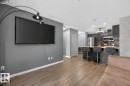 Living area featuring wide plank flooring and an open concept kitchen with stainless steel appliances, dark cabinetry, and a peninsula with seating - 109 340 Windermere Road, Edmonton, AB 