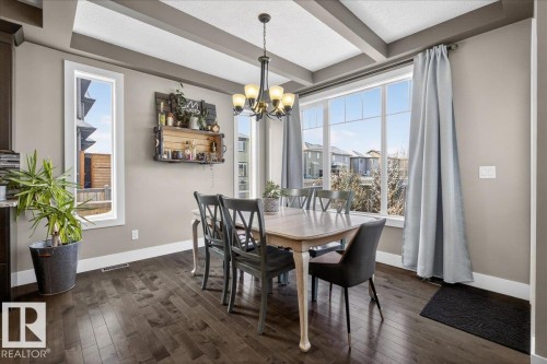 Dining area featuring rich hardwood floors and abundant natural light from large windows - 606 Reynalds Way, Leduc, AB - Indoor Photo Showing Dining Room