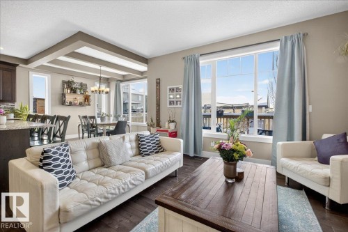 The property features an open-concept living area with dark wood flooring - 606 Reynalds Way, Leduc, AB - Indoor Photo Showing Living Room