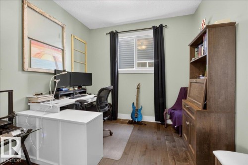 This room features hardwood flooring, a window with black curtains, and light-colored walls - 606 Reynalds Way, Leduc, AB - Indoor Photo Showing Office