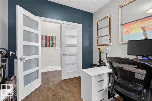This interior space features hardwood flooring and modern white doors with frosted glass panels - 606 Reynalds Way, Leduc, AB - Indoor