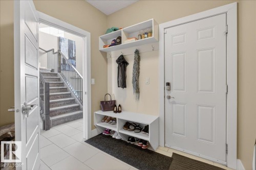 Entryway featuring a white paneled door, a built-in storage bench with shelving, and white tile flooring - 606 Reynalds Way, Leduc, AB - Indoor Photo Showing Other Room