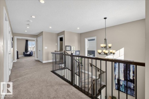 The property features an open landing with light beige walls and a carpeted floor - 606 Reynalds Way, Leduc, AB - Indoor Photo Showing Other Room