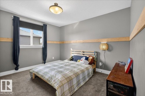 The room features a window with dark curtains, a ceiling light fixture, and a bed frame - 606 Reynalds Way, Leduc, AB - Indoor Photo Showing Bedroom