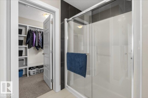 The property features a shower with a clear glass enclosure and a walk-in closet with built-in shelving and hanging space - 606 Reynalds Way, Leduc, AB - Indoor